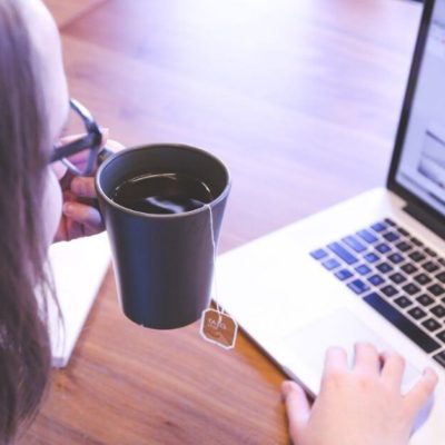 Woman working on her laptop while drinking a cup of tea