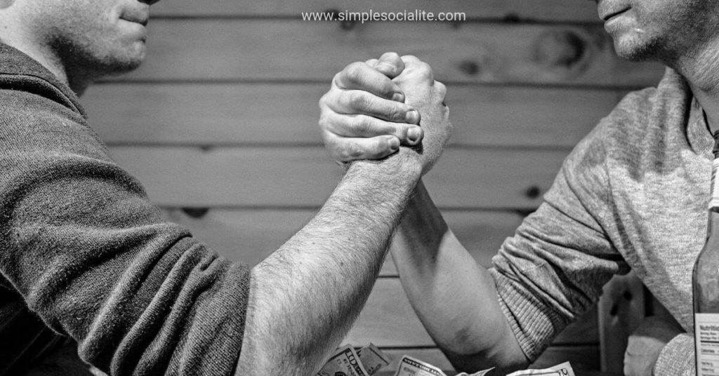 Two guys arm wrestling trying to compare themselves to the other