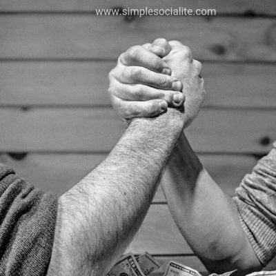 Two guys arm wrestling trying to compare themselves to the other