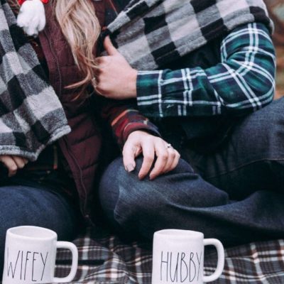 Couple enjoying a budget-friendly picnic while bundled up in a blanket together