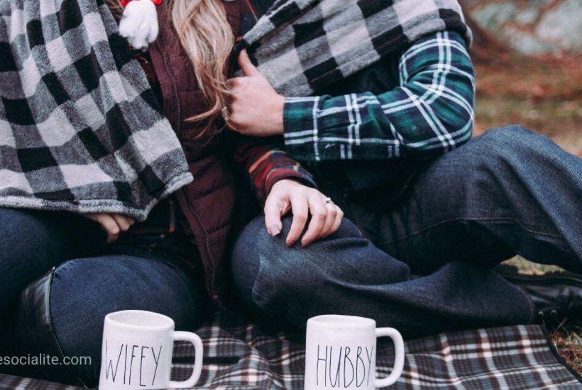 Couple enjoying a budget-friendly picnic while bundled up in a blanket together