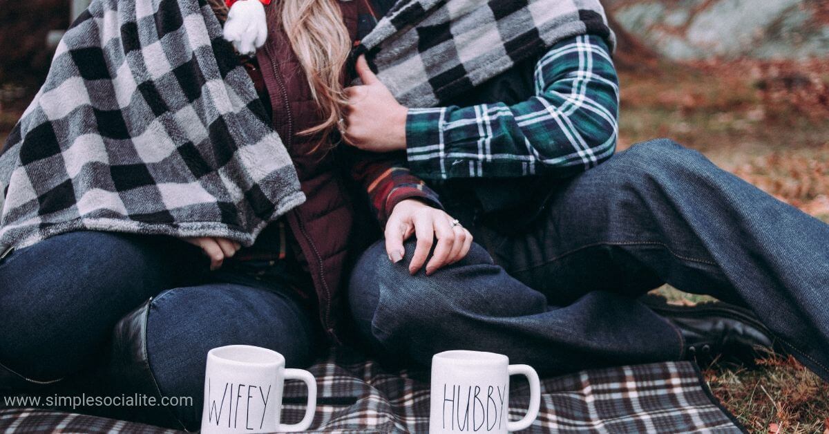 Couple enjoying a budget-friendly picnic while bundled up in a blanket together